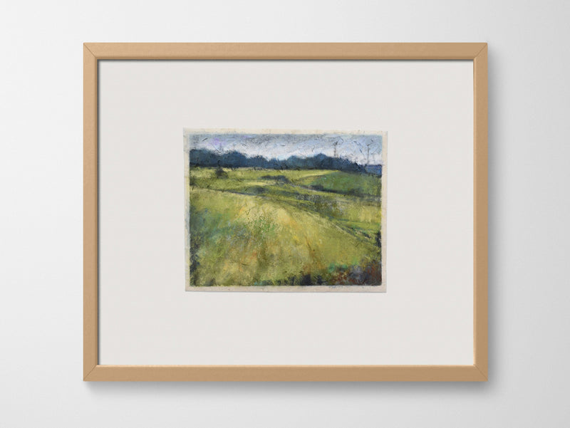 a framed artwork of fields on a white wall