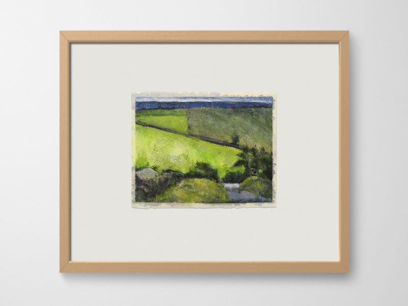 a framed artwork of fields on a white wall