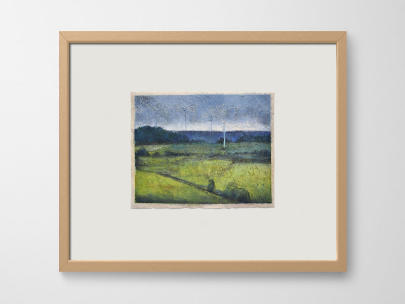 a framed artwork of fields on a white wall