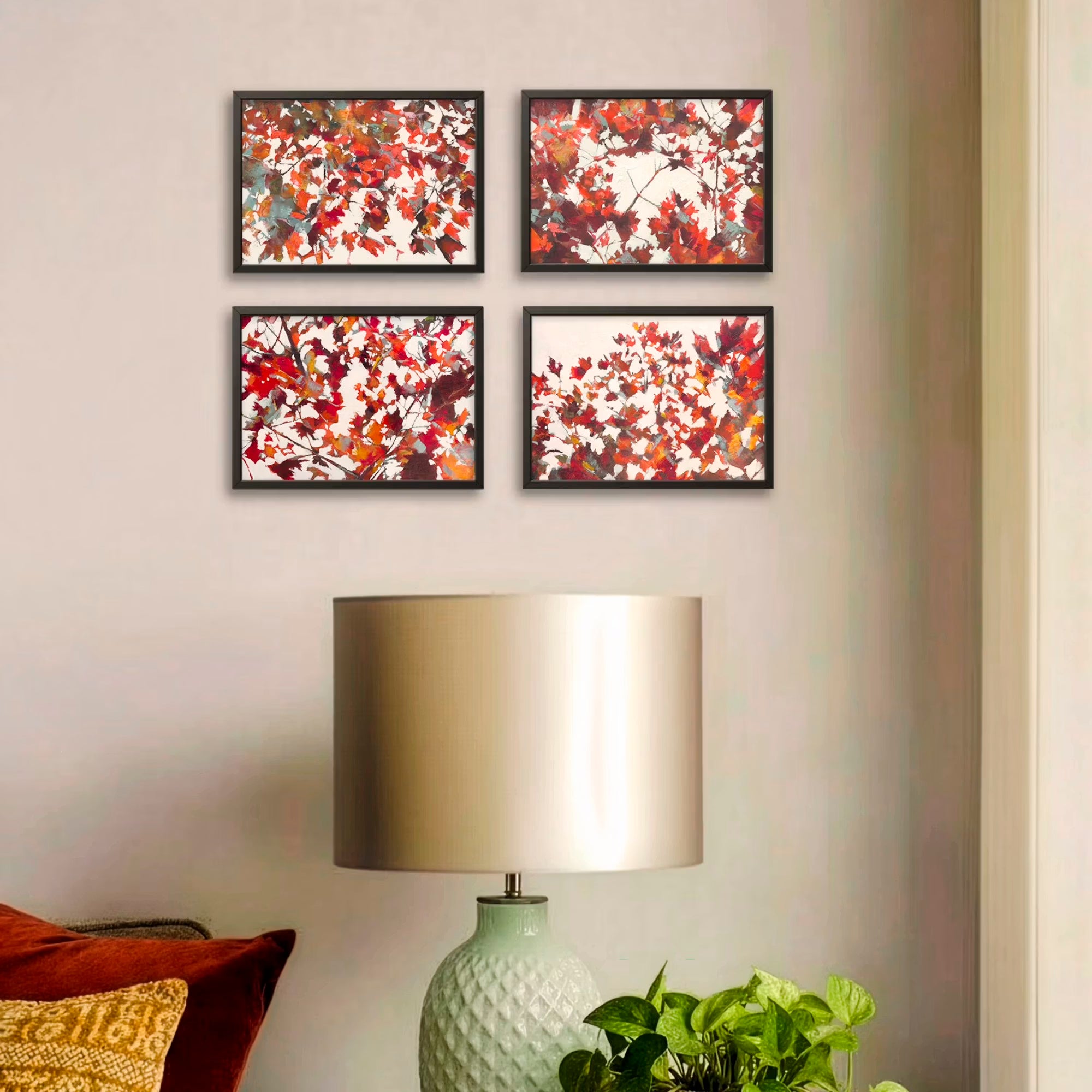 Room showing the Escape from The Grey collection of 4 small oil paintings by Julia Brown, hanging over a lamp and gold and red cushions