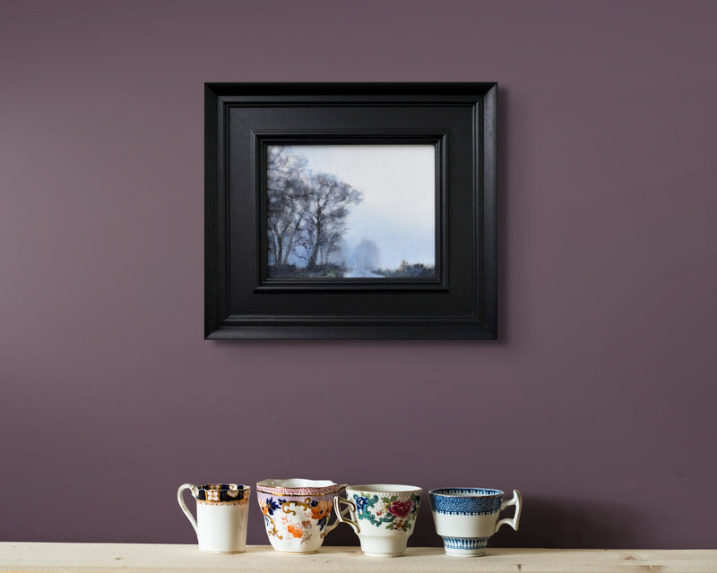 a small oil painting of misty trees in greys and purples on a purple wall